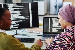 two women infront of a PC displaying Code