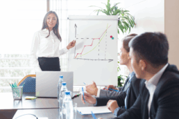 A lady standing at a whiteboard with a graph on an upward trend