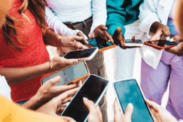 A group of people standing in a circle on their mobile phones
